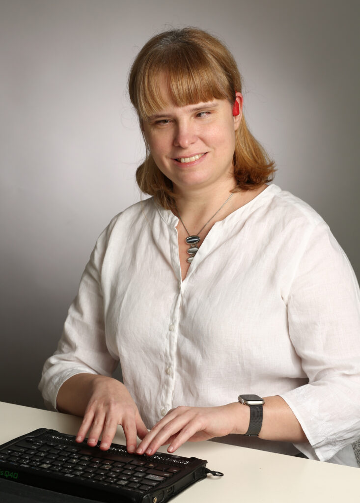 blonde Frau mit weißem Hemd an einer Baillie-Tastatur
